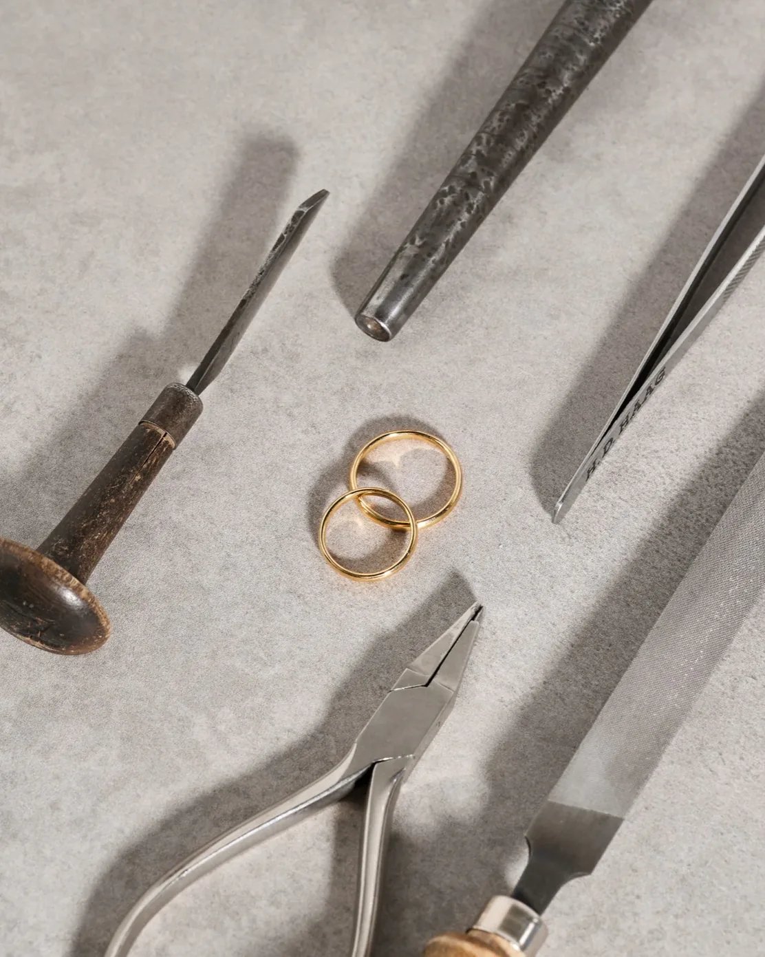 Zwei goldene Ringe zwischen alten Goldschmiedewerkzeugen