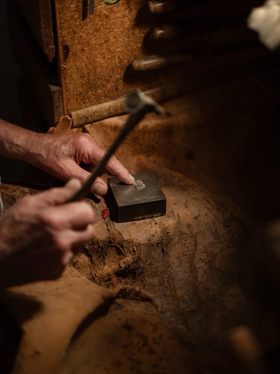 Hände mit Hammer und Punze an der Werkbank